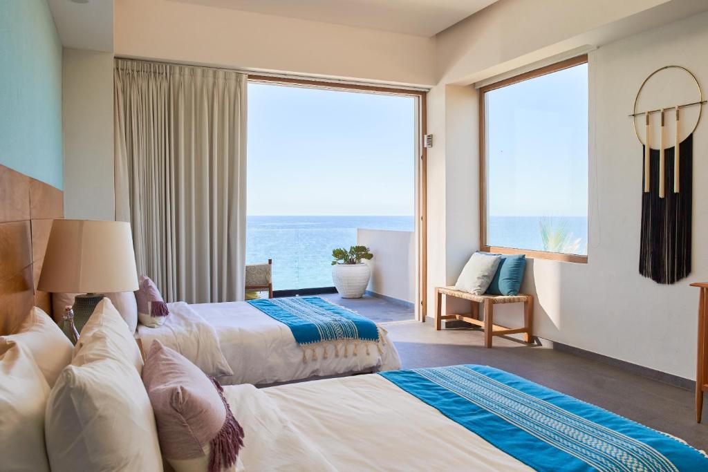 two beds in a room with a view of the ocean at Hotel Basalto in Punta Mita