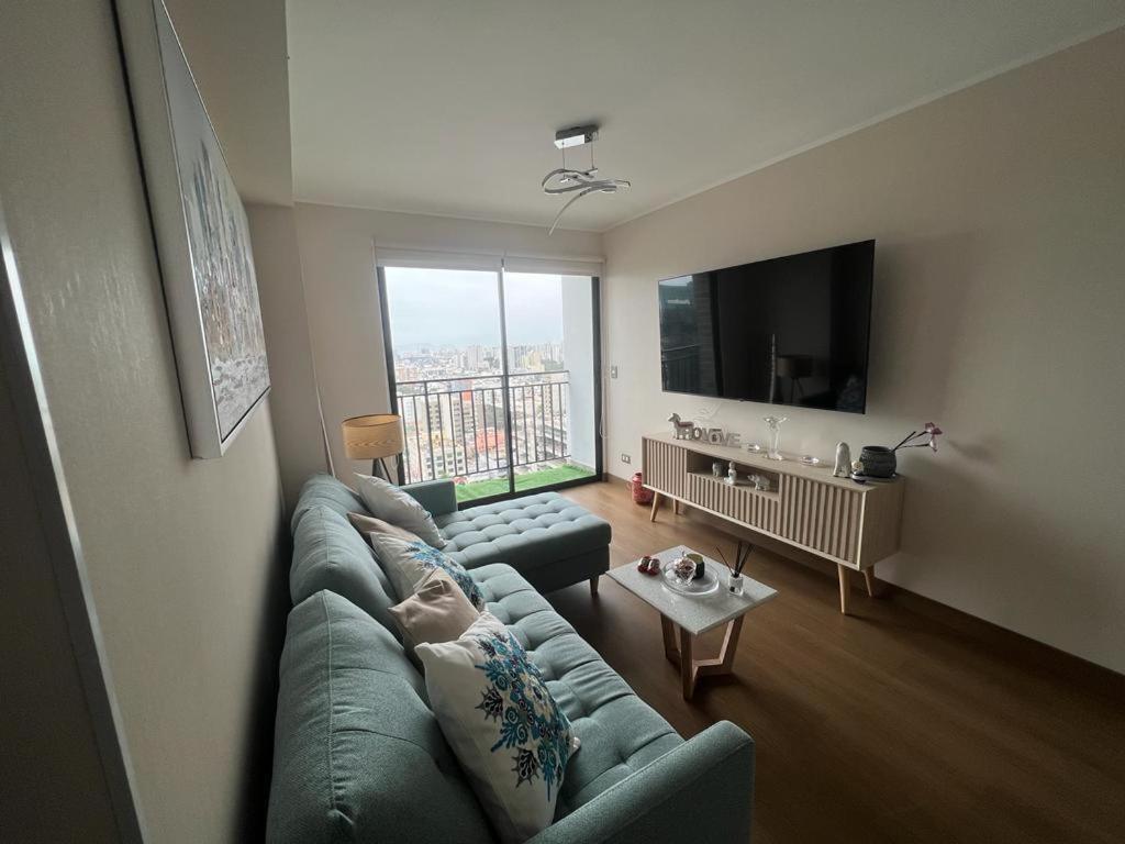 a living room with a green couch and a large window at Aparment Deluxe San Isidro in Lima