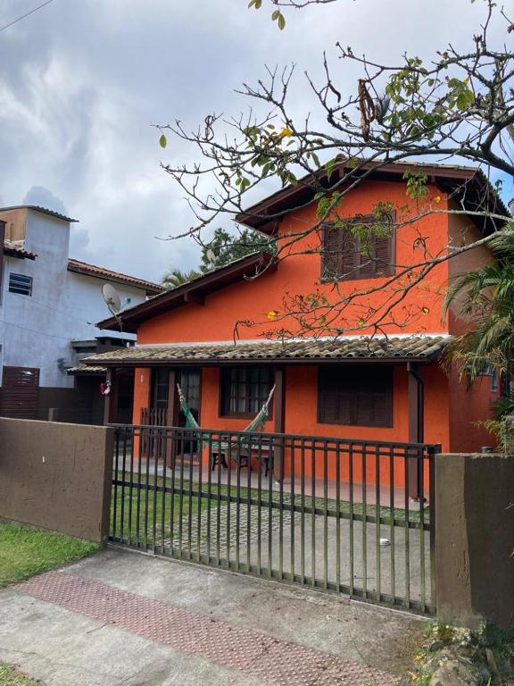 an orange house with a fence in front of it at Residencial Casa Laranja - Casas na Praia da Ferrugem in Garopaba