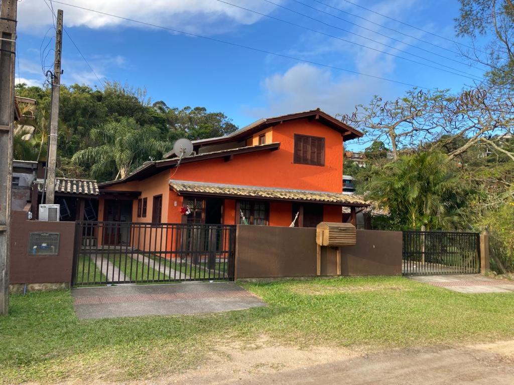 a orange house with a gate in front of it at Residencial Casa Laranja - Casas na Praia da Ferrugem in Garopaba