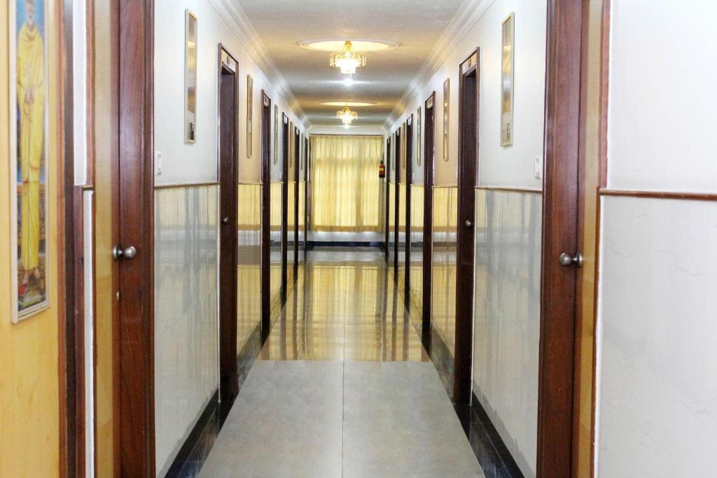 un pasillo vacío con puertas de madera y un pasillo en OYO Hotel Ganga Sagar Near Sri Someshwara Swami Temple, en Bangalore