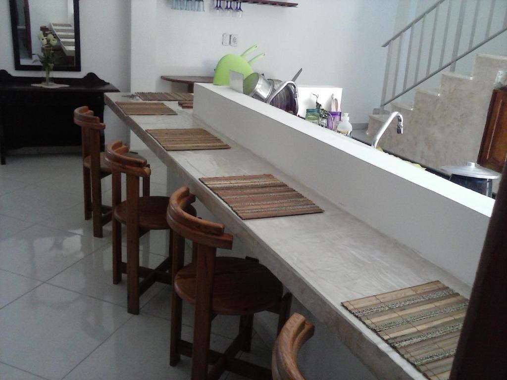 a kitchen with a long counter with chairs around it at Casa Pontal Ilheus in Ilhéus