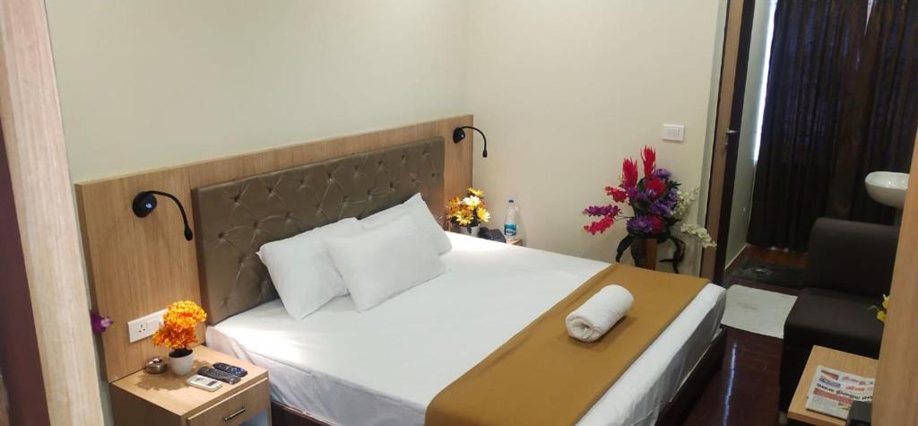 una habitación de hotel con una cama grande y una silla en Hotel Amutham, en Tiruchchirāppalli