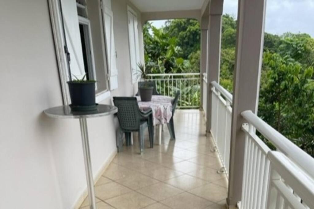 a porch with a table and chairs on a balcony at VILLA NATURE in Baie-Mahault
