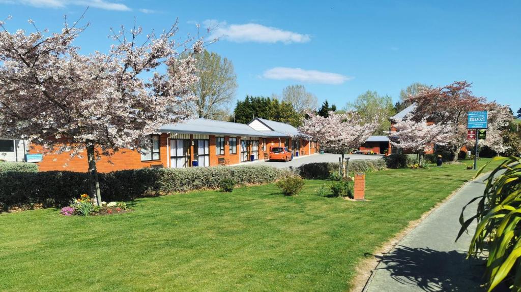 a building with flowering trees in front of a yard at Broadview Motel in Cheviot