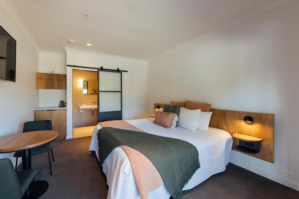ein Hotelzimmer mit einem großen Bett und einem Tisch in der Unterkunft Eleven in Daylesford