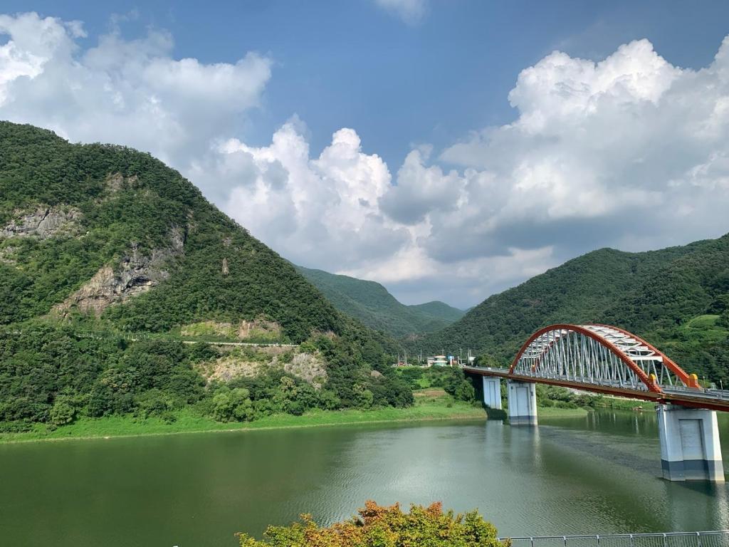 a bridge over a river with mountains in the background at Danyang Rio 127 Guesthouse in Danyang