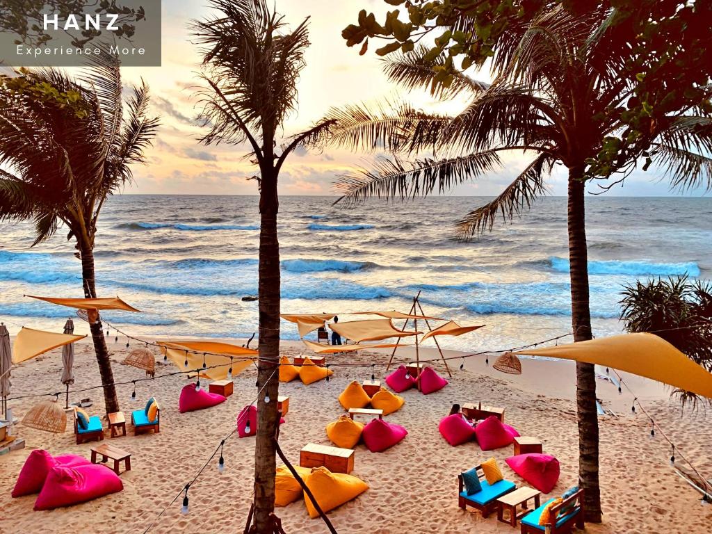 einen Strand mit Stühlen, Palmen und dem Meer in der Unterkunft HANZ AND Sunset Beach Resort in Phu Quoc