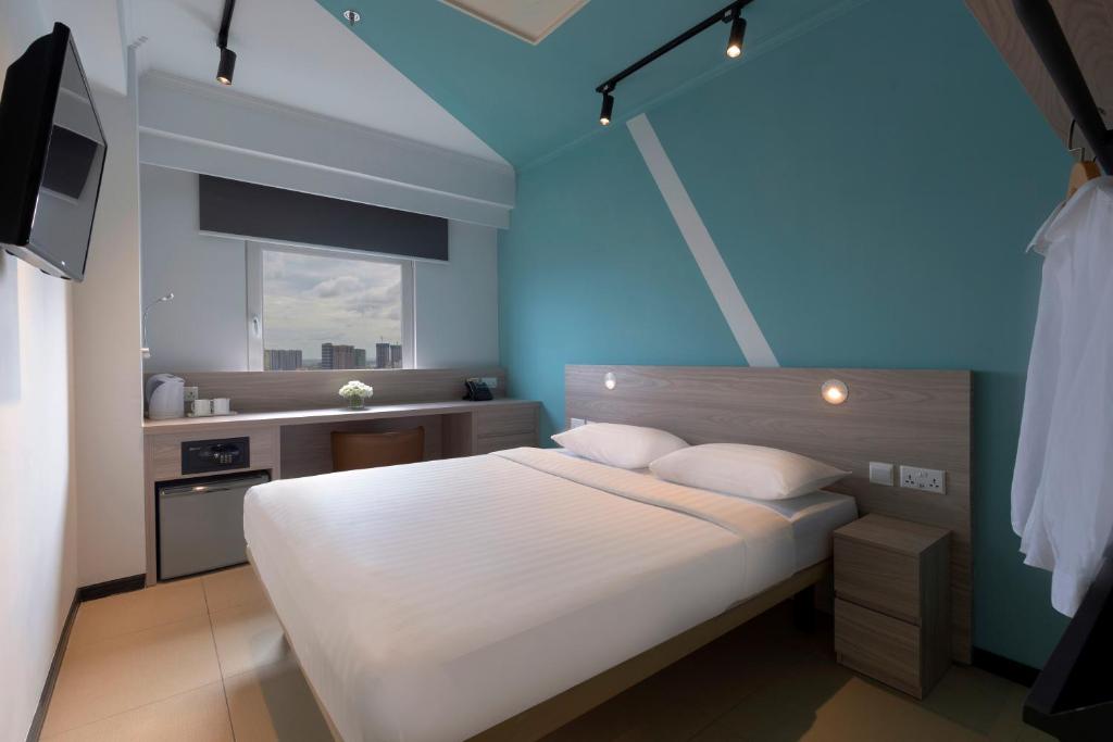 a bedroom with a white bed and a blue wall at ibis budget Phnom Penh Riverside in Phnom Penh