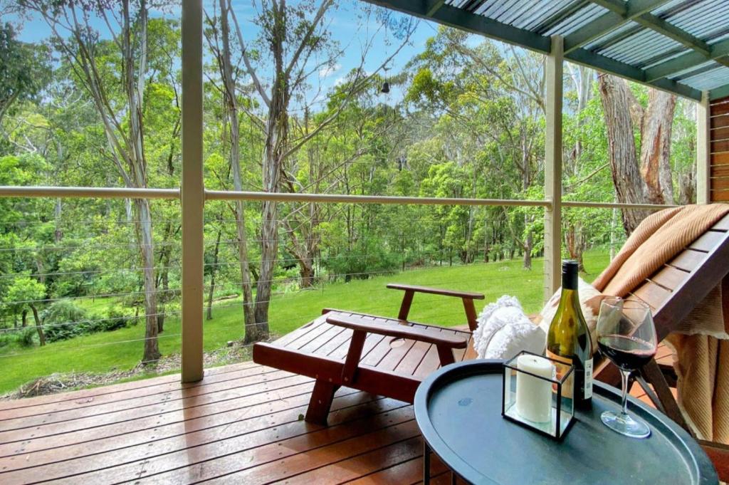 a porch with a bench and a table with a bottle of wine at Mirimvale - Base of Mt Buller - Sleeps 14 in Merrijig