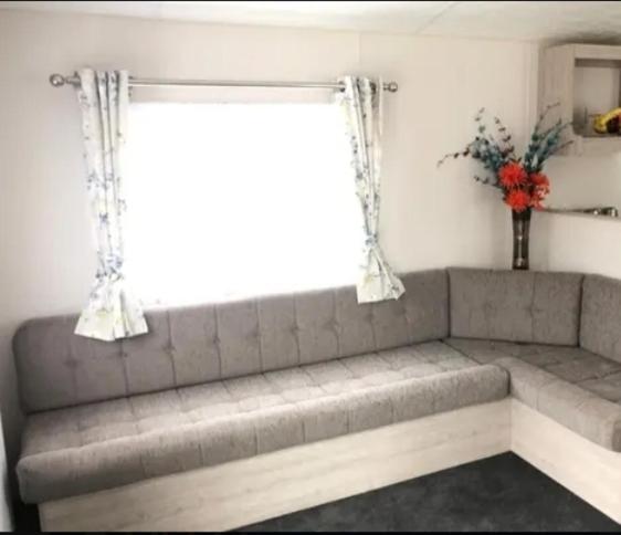 a couch in a living room with a window at Greenhouse 24 in Little Clacton