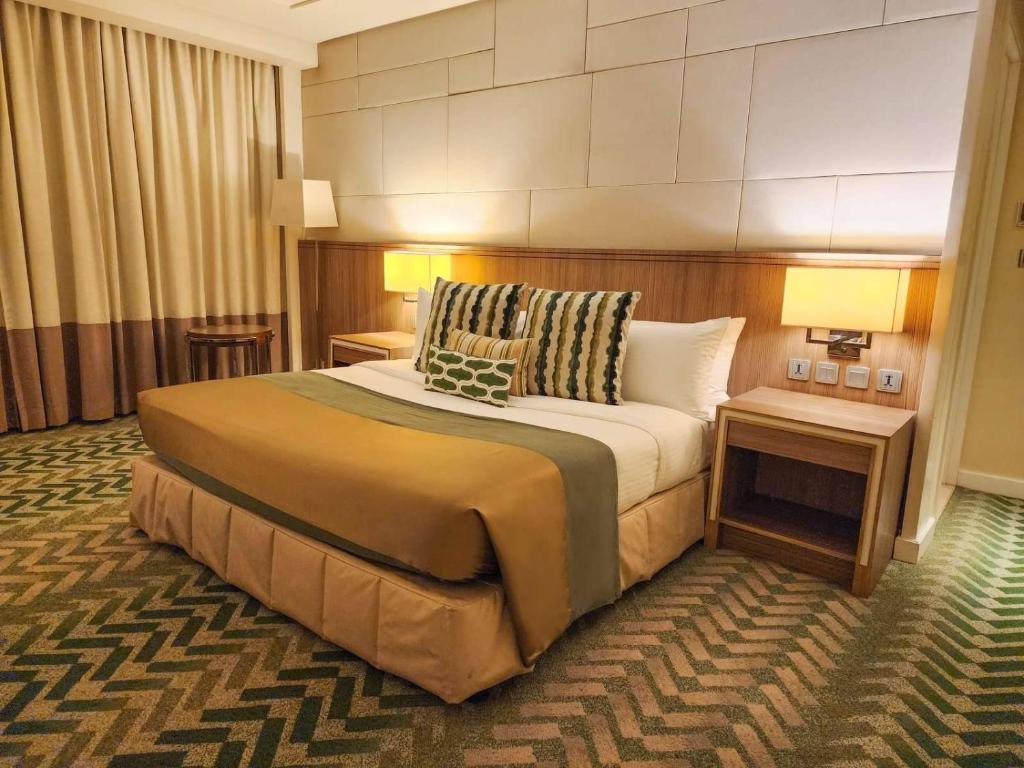 a hotel room with a large bed with two tables at Hotel Benilde Maison De La Salle in Manila