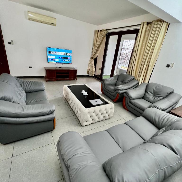 uma sala de estar com sofás e uma televisão em En-Suite Rooms W/Pool & Gym in Mikocheni Near Beach em Dar es Salaam
