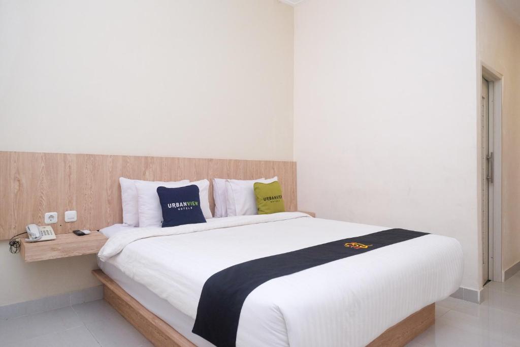 1 dormitorio con 1 cama blanca grande y cabecero de madera en Urbanview Hotel DJ Inn Tegal, en Tegal