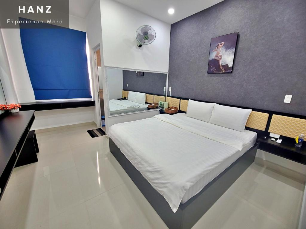- une chambre avec un grand lit et un mur bleu dans l'établissement HANZ Hung Phu Hotel, à Hô-Chi-Minh-Ville