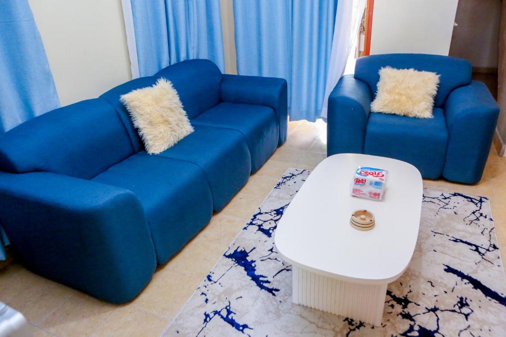 Sala de estar con 2 sofás azules y mesa de centro en SYLVIA'S LUXURIOUS APARTMENT, en Kisumu