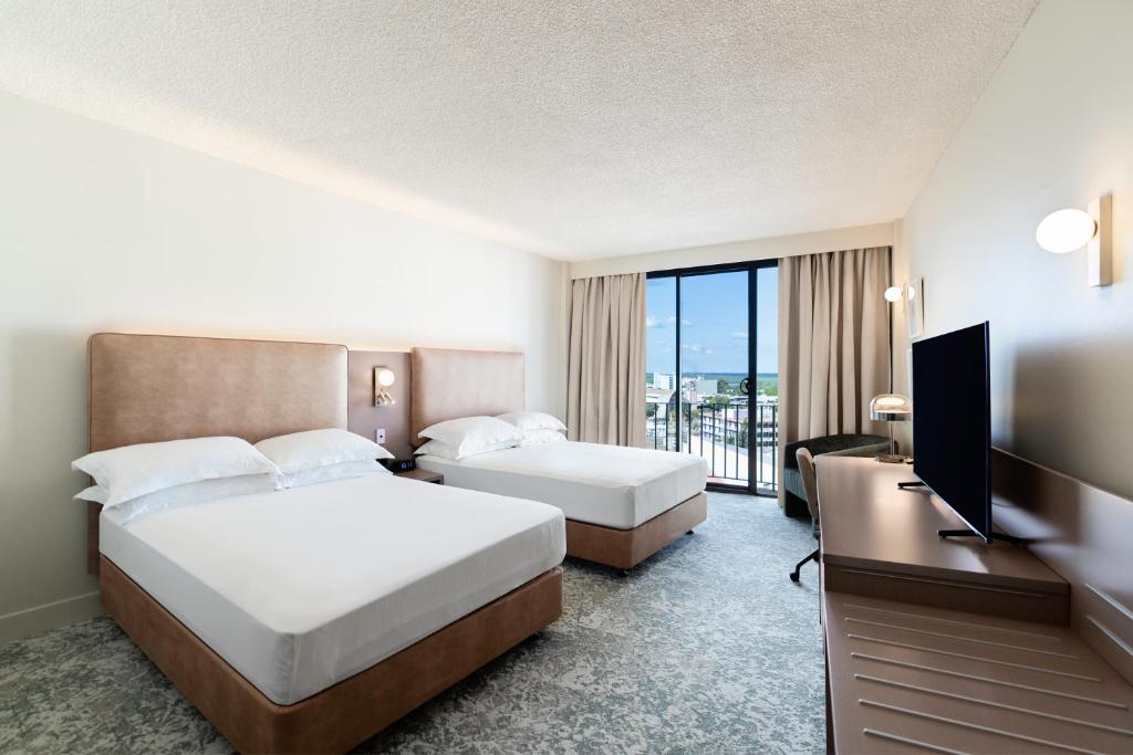 a hotel room with two beds and a flat screen tv at Hilton Garden Inn Darwin in Darwin