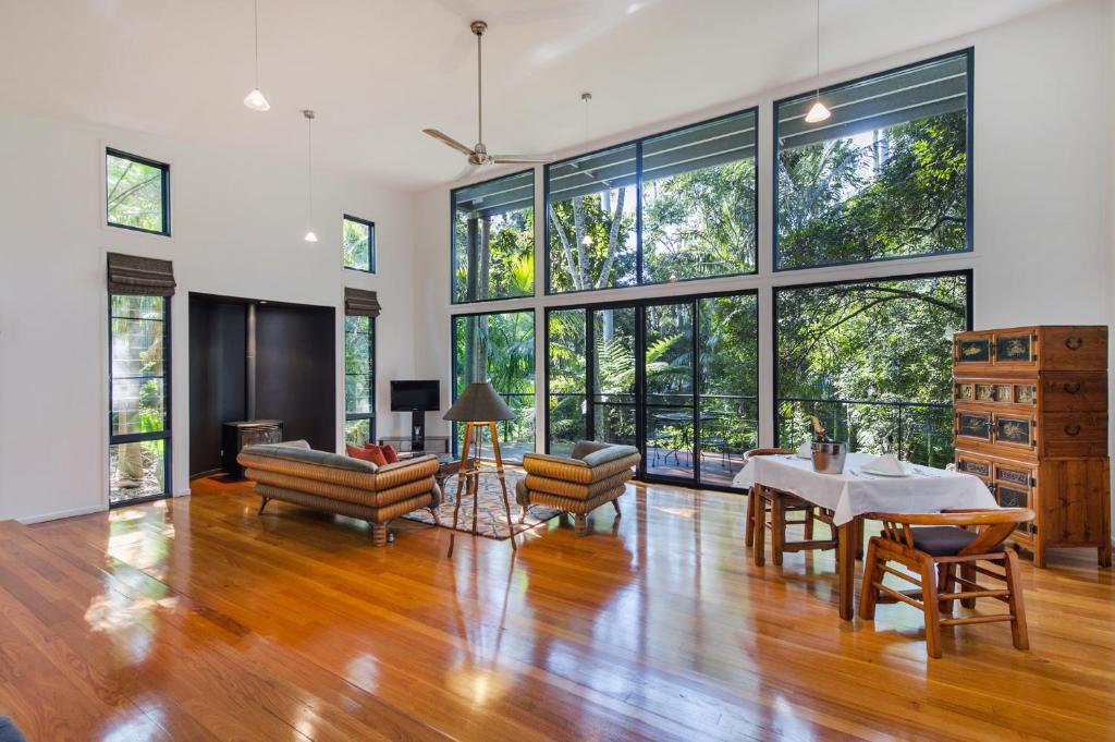 - un salon avec une table, des chaises et de grandes fenêtres dans l'établissement Pethers Rainforest Retreat, à Mount Tamborine