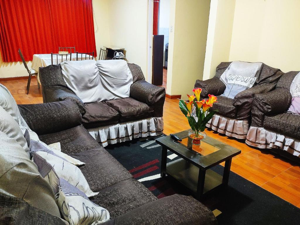 - un salon avec des canapés et une table avec des fleurs dans l'établissement Fernanda apartment, à Arequipa