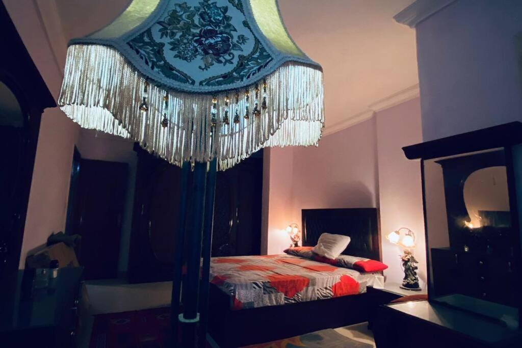 um quarto com uma cama e um grande lustre em Luxury apartment by the sea! em Alexandria