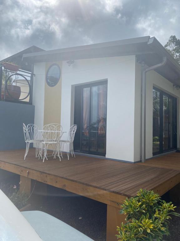 a house with a wooden deck with a table and chairs at LE BOURBON POINTU in Le Tampon