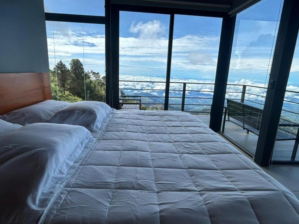 a bedroom with a large bed with a view of the ocean at Villas Páramo Cloud Forest Hotel in División