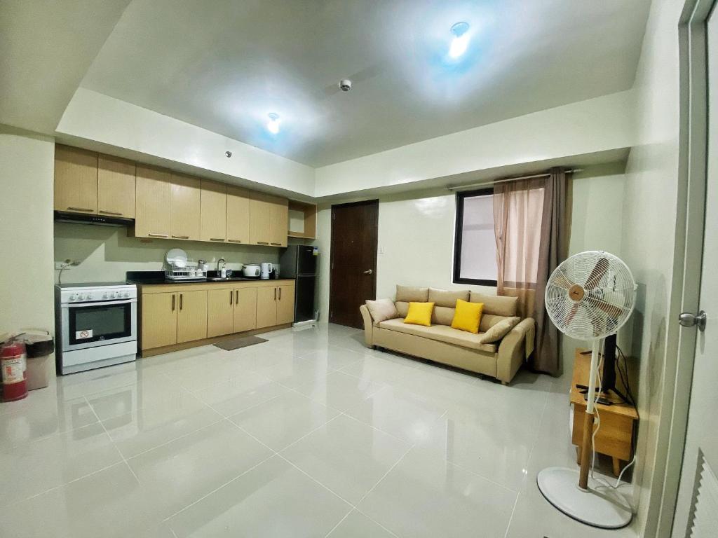 Il dispose d'une grande cuisine et d'un salon avec un canapé et un ventilateur. dans l'établissement QFandZ Baguio Homestay at Brenthill Condominium, à Baguio
