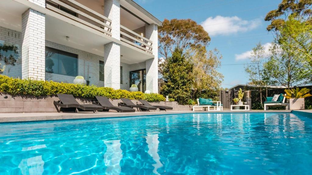 a swimming pool with chairs next to a house at MondoDan in McCrae