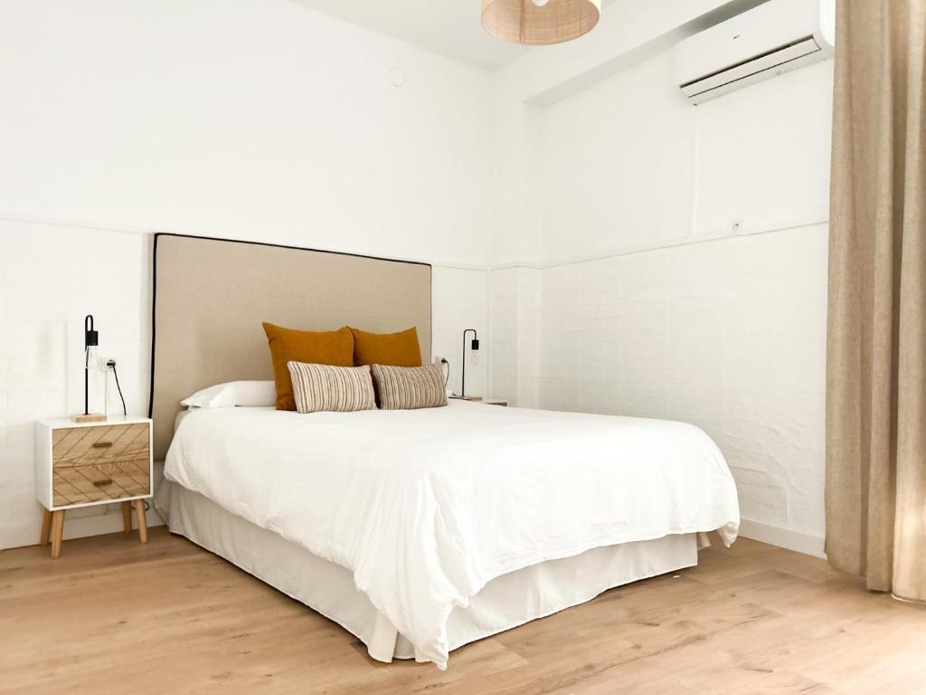 1 dormitorio blanco con 1 cama blanca grande con almohadas de color naranja en Apartamento Plaza en Castilleja de la Cuesta