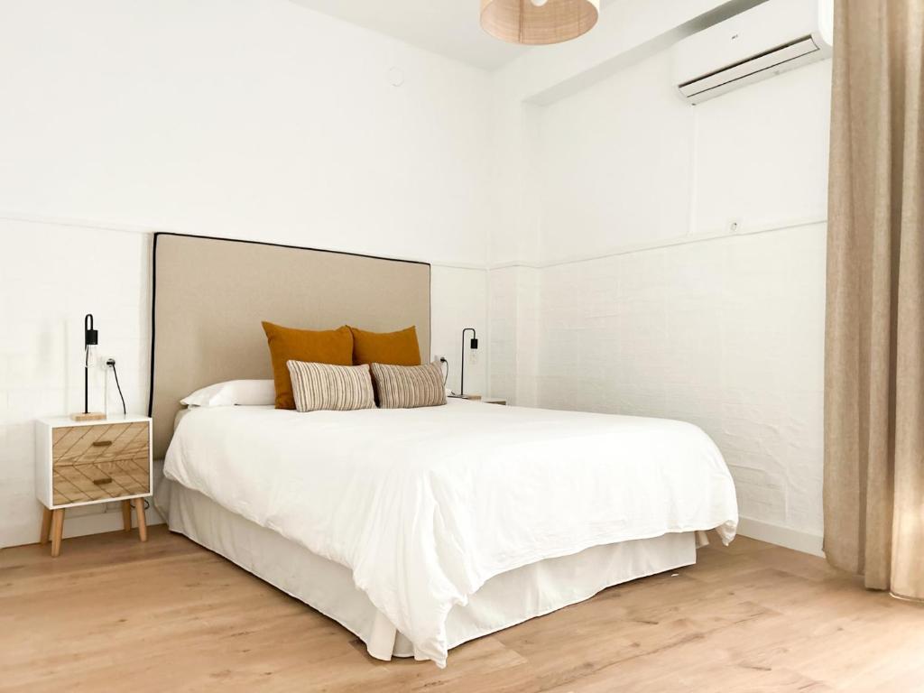 1 dormitorio blanco con 1 cama blanca grande con almohadas de color naranja en Apartamento Plaza, en Castilleja de la Cuesta