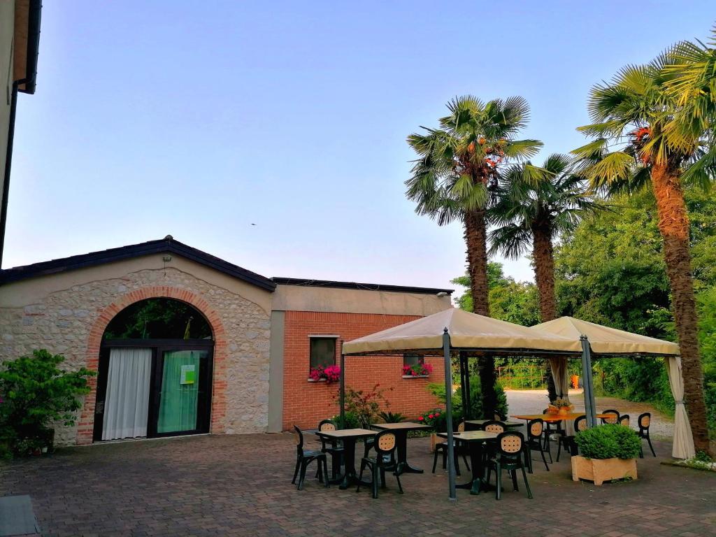 a patio with tables and chairs and palm trees at Agriturismo Da Andreina in Borso del Grappa