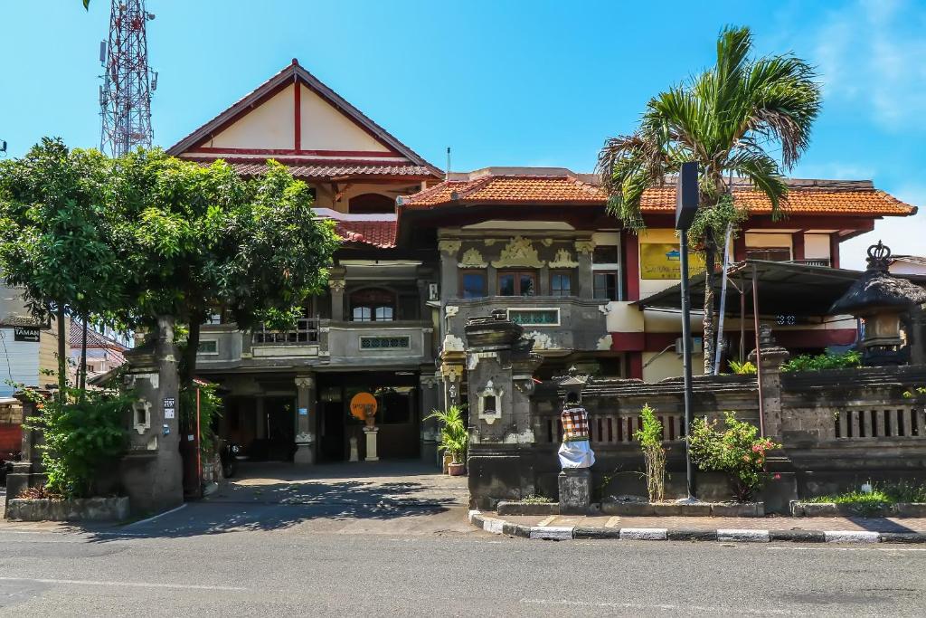 a large building with palm trees in front of it at SUPER OYO 1927 Hotel Candra Adigraha in Denpasar