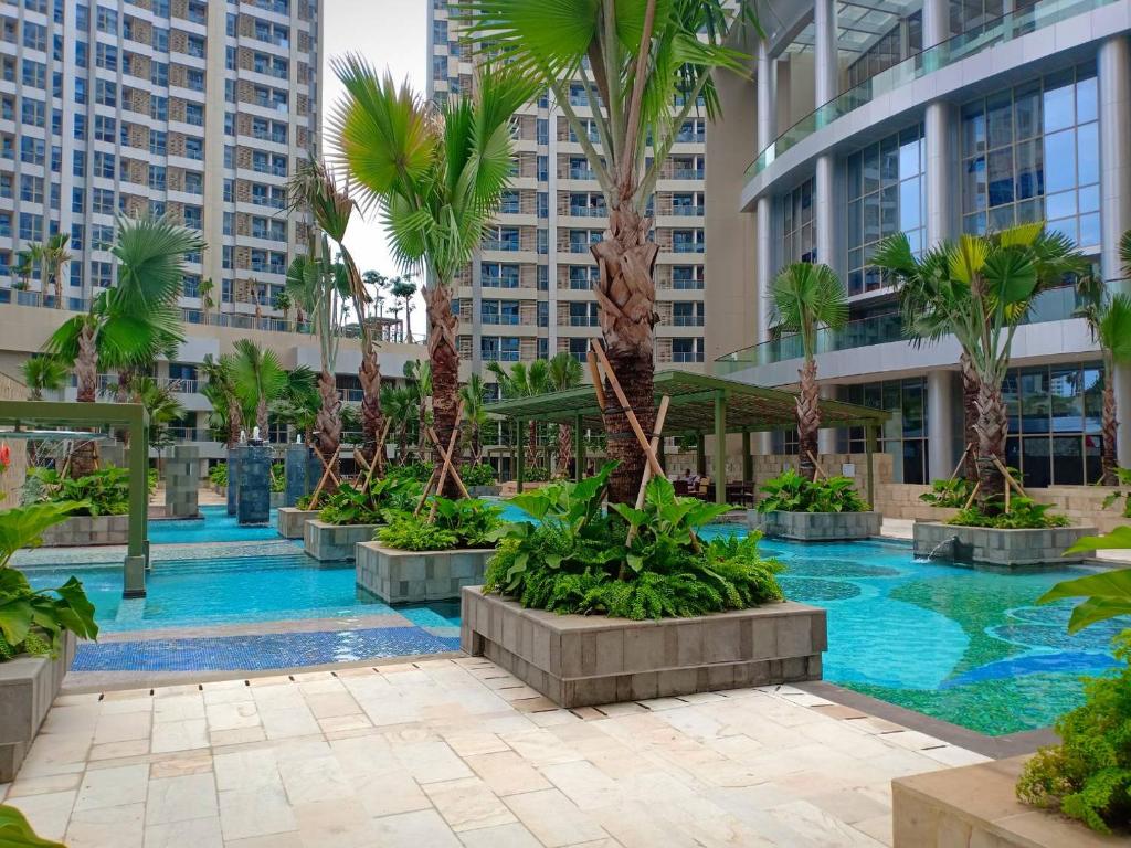 une piscine au milieu d'un immeuble avec des palmiers dans l'établissement Studio 17 Taman Anggrek Residence Best Cozy and Stay 50mbps Wifi, à Jakarta