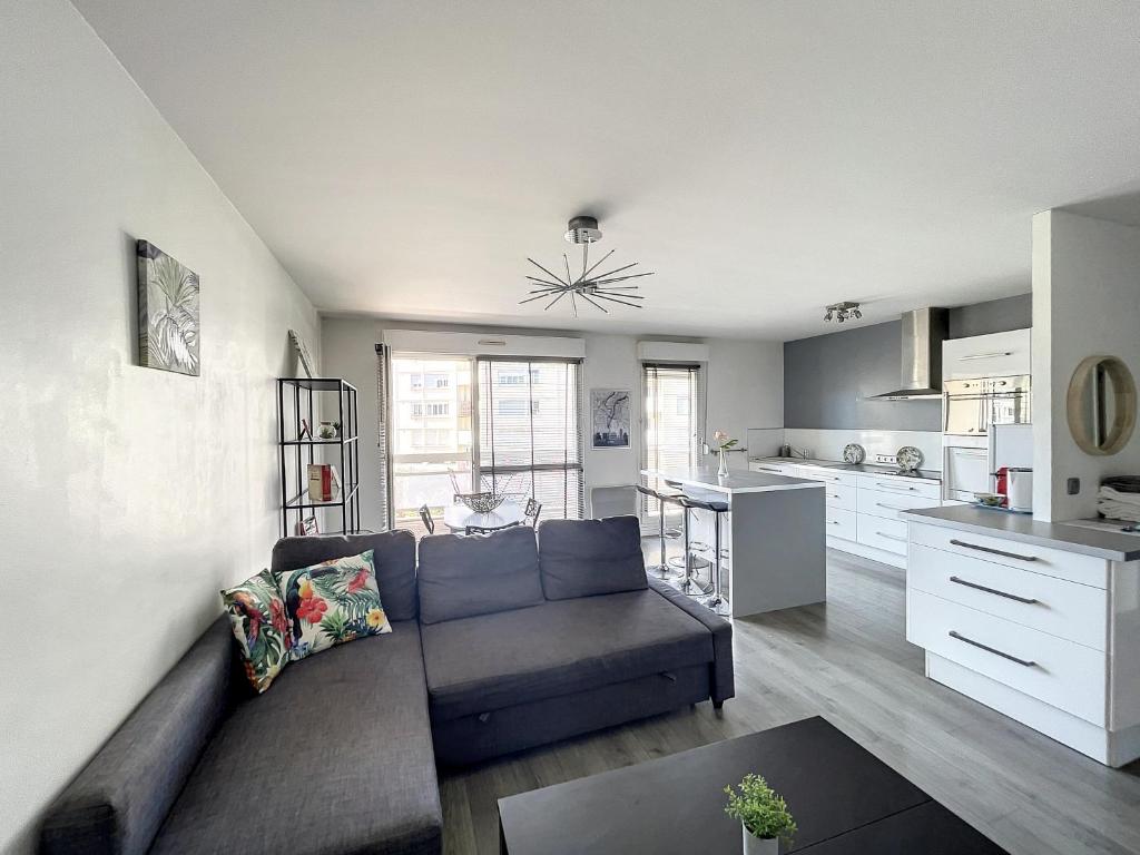 a living room with a couch and a kitchen at City & cosy, LYON CHARCOT- WIFI - LAVE LINGE - BALCON - PARKING in Lyon