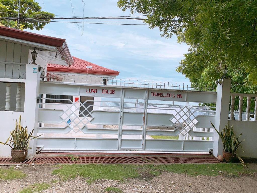 a white house with a gate in front of it at LUNA OSLOB TRAVELLERS INN - Beach Front in Oslob