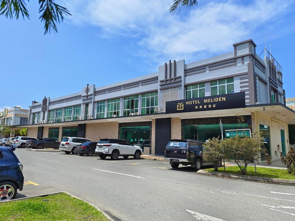 a building with cars parked in a parking lot at Hotel Meliden in Sandakan