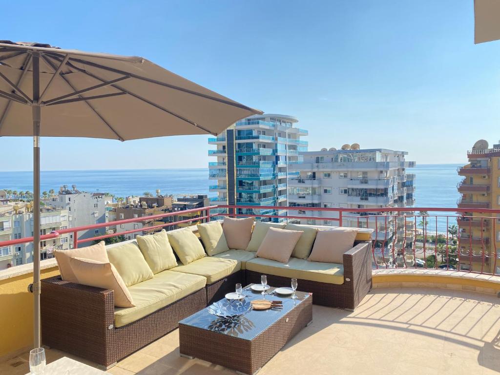 un sofá sentado en un balcón con sombrilla en Penthouse Paradise in Mahmutlar, en Alanya