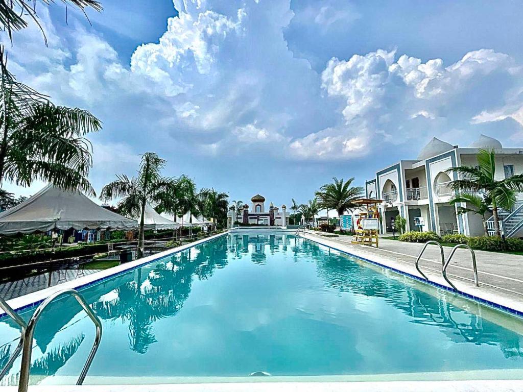 une piscine dans un complexe avec de l'eau bleue et des palmiers dans l'établissement Torres Farm Resort powered by Cocotel, à Naic