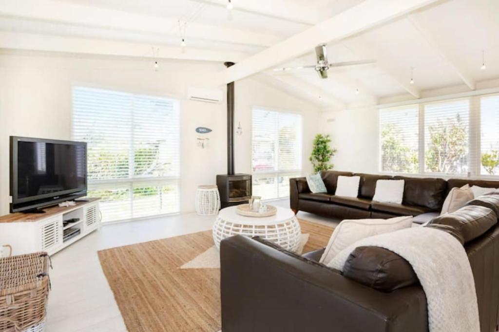 a living room with a couch and a tv at Heales Hideaway Dromana steps to the beach in Dromana