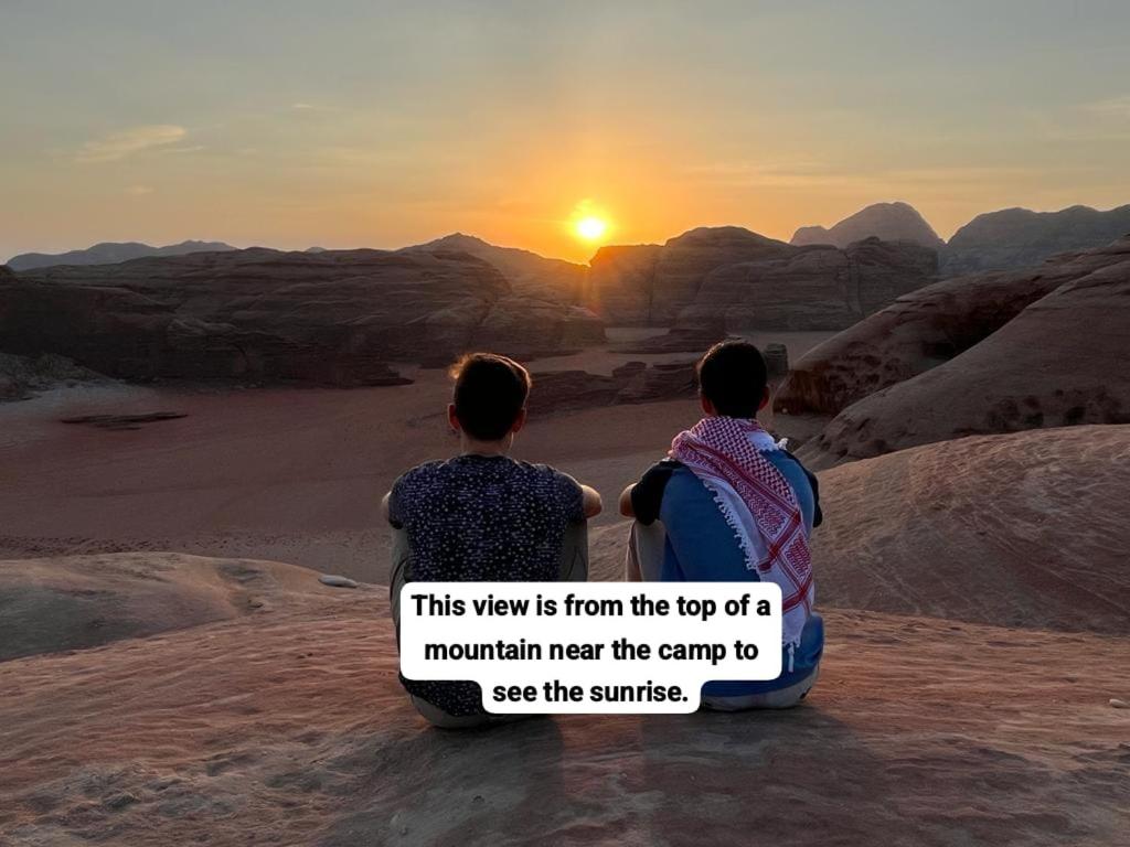 瓦迪拉姆的住宿－Bedouin Tours Camp，两人坐在沙漠里,欣赏日落