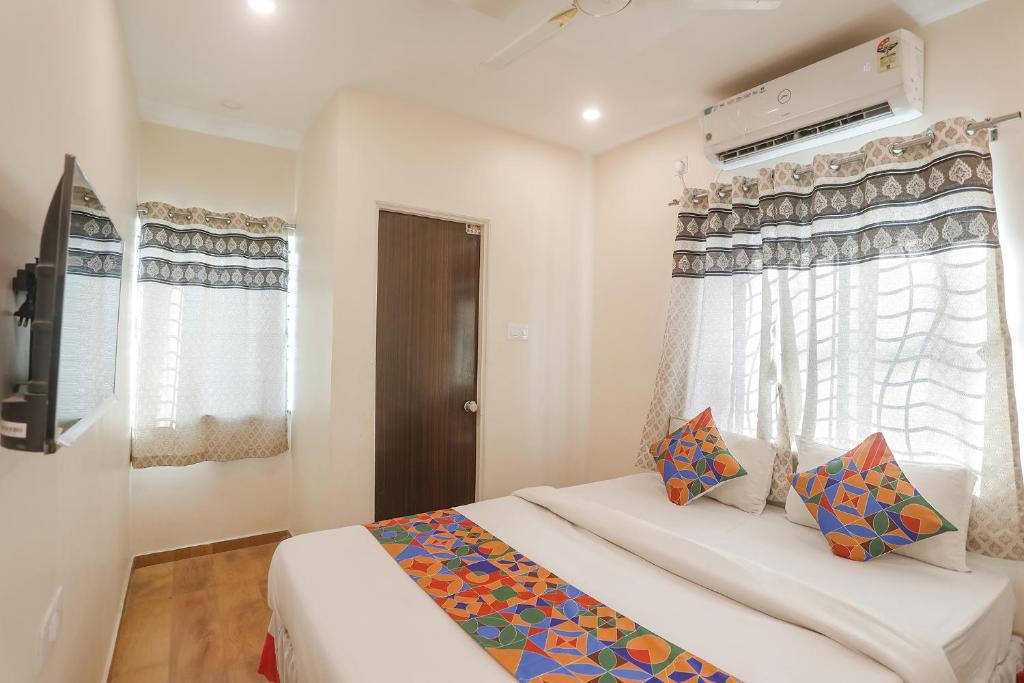 a bedroom with a bed and a tv and windows at FabExpress Shivas Inn in Nagpur