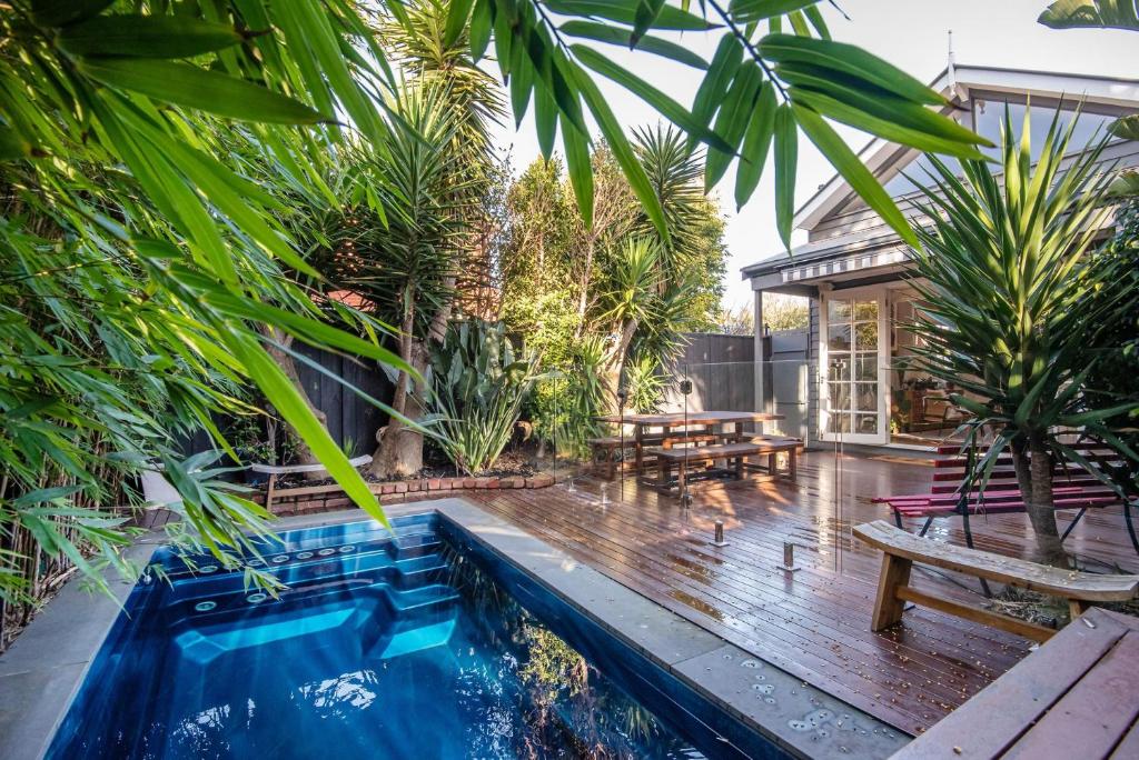 a backyard with a pool and a house with palm trees at Sandy Village Retreat Heated Pool Bay Views in Sandringham