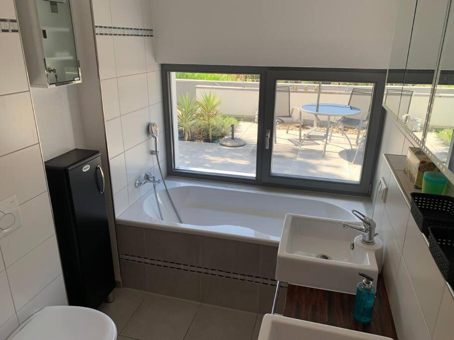baño con bañera, lavabo y ventana en Panorama Apartment, en Kandern