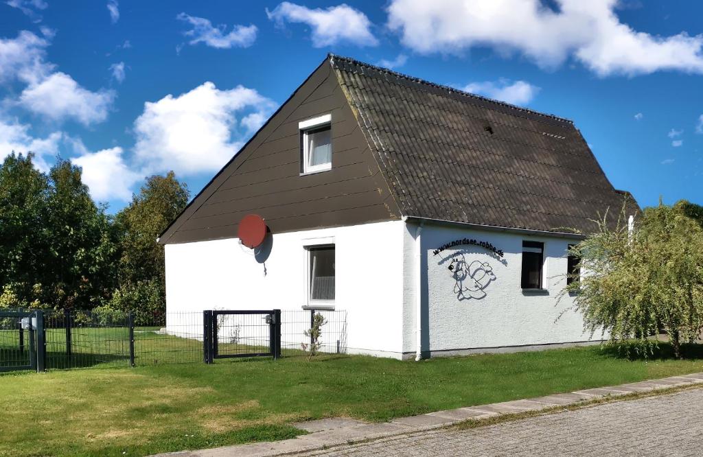 een klein wit gebouw met een zwart dak bij Ferienhaus Nordsee-Robbe in Eckwarderhörne