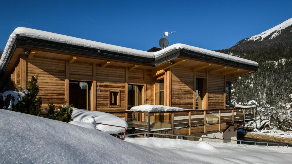 Cabaña de madera con nieve en el porche en Chalet Base Camp, en Les Houches