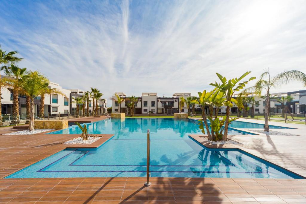 uma grande piscina com palmeiras e edifícios em ALEGRIA ID25 em Playa Flamenca