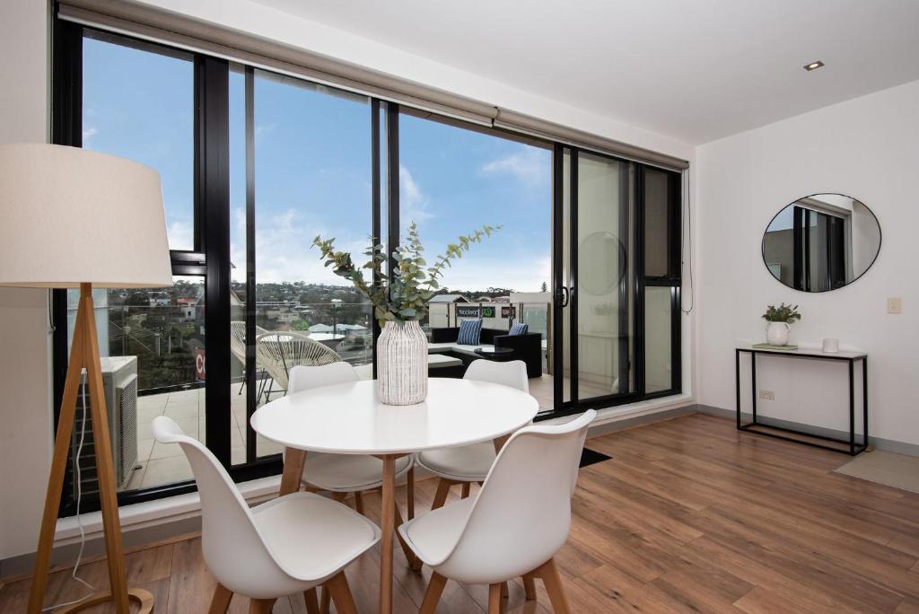a dining room with a white table and chairs and large windows at Aqua Views of the bay in Mornington in Mornington
