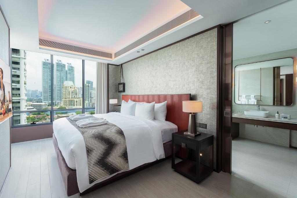 A bright bedroom pairing a king bed with a broad Bangkok skyline view.