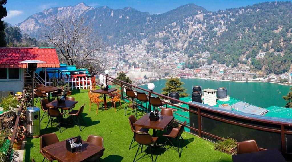 a balcony with tables and chairs and a boat on the water at Aman The Lake Side Hotel in Nainital