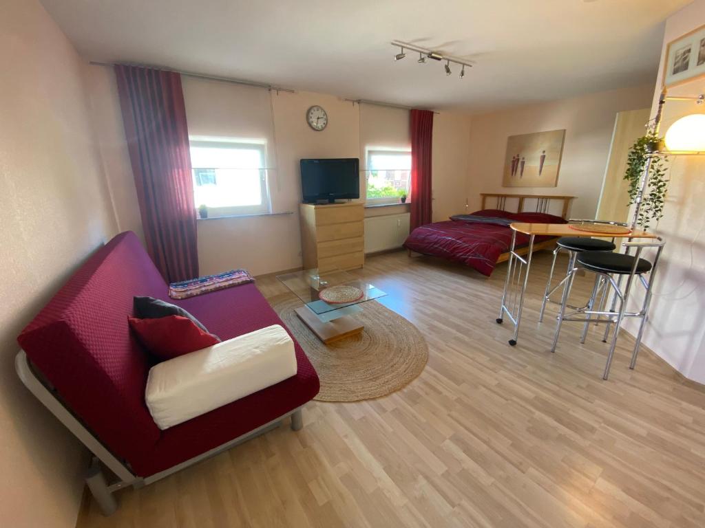 - un salon avec un canapé rouge et une table dans l'établissement Gemütliches Ferienapartement, à Cassel